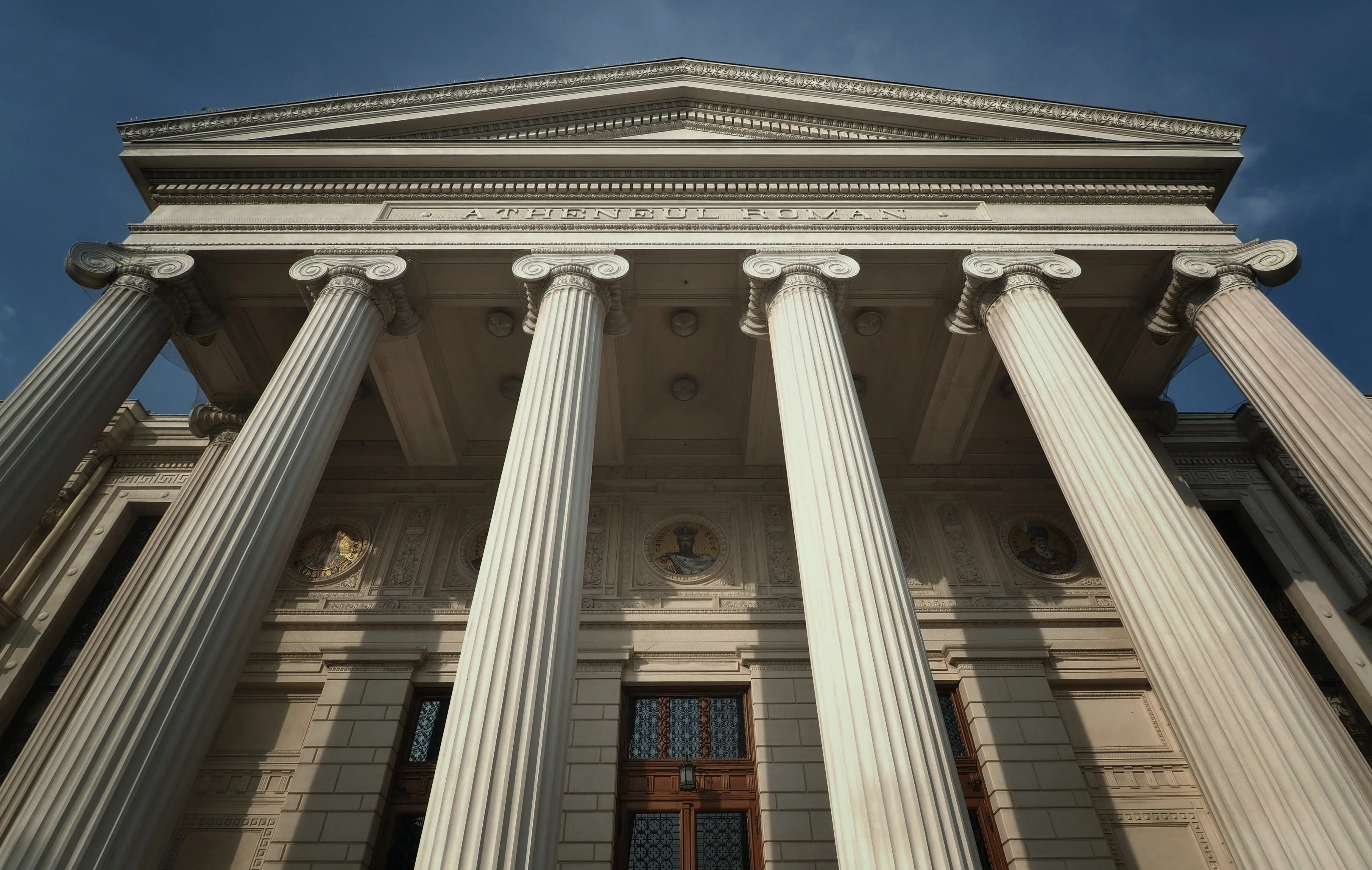 The colonnade of a neoclassical concert hall, a characteristic setting for scholarly convening.